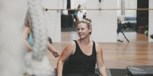 Paraplegic woman approaches ropes and crash mats in a gym