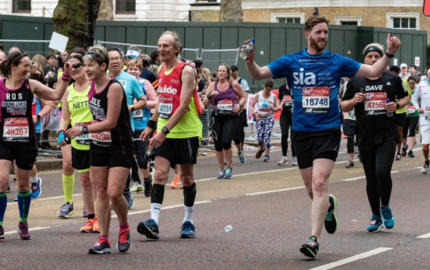 A photo of runners at the 2021 London Marathon with one man wearing a t-shirt that has the Spinal Injuries Association logo on it.
